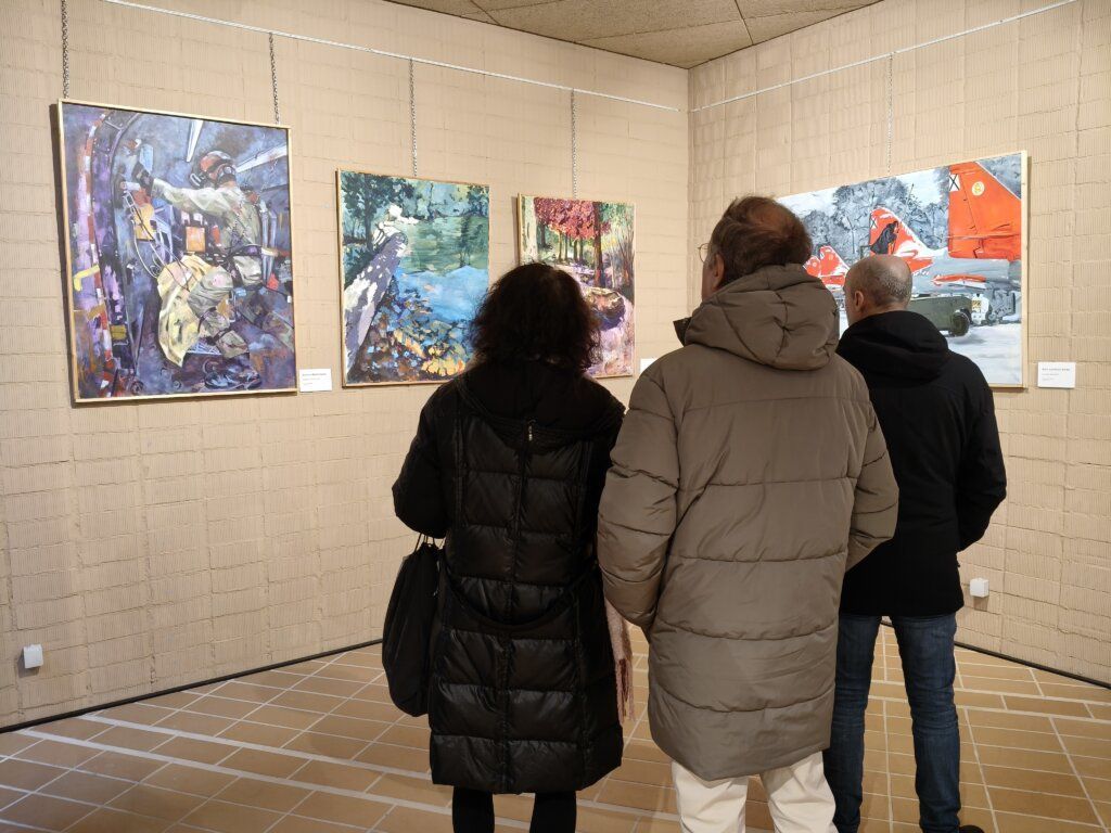 Personas observando obras de arte en una exposición en Carbajosa de la Sagrada.