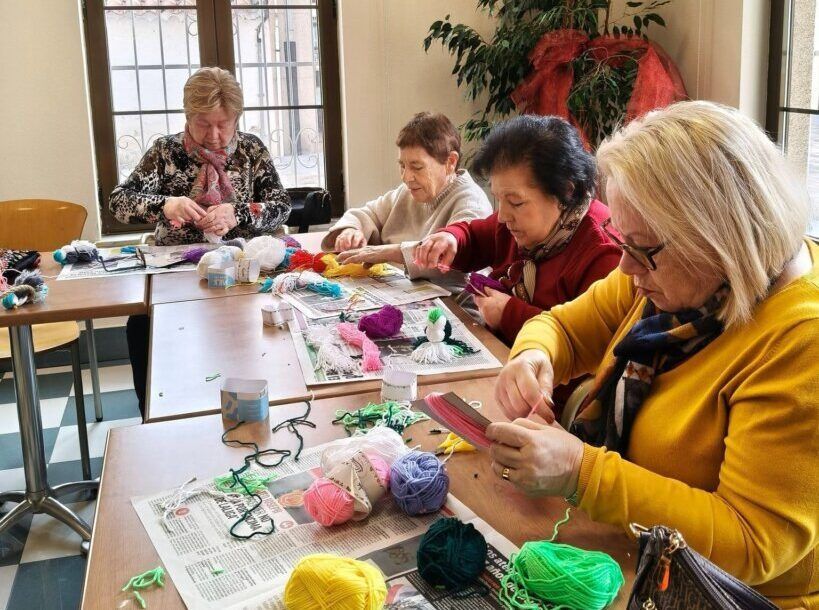Grupo de mayores participando en un taller creativo con hilos de colores