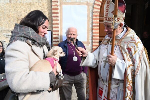 El obispo bendice a una mujer con su perro durante la festividad de San Antón.