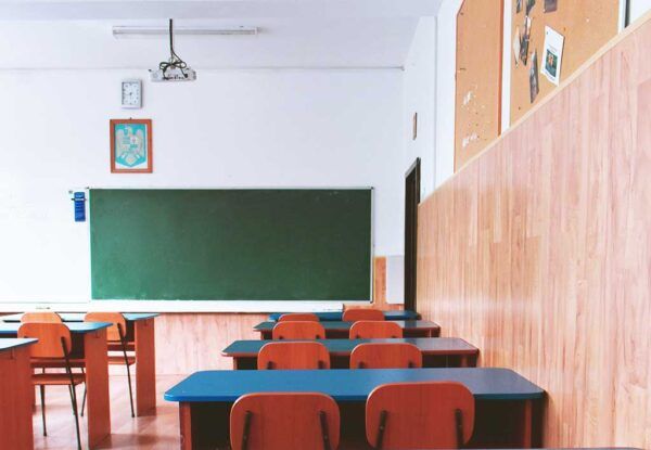 Interior de un aula con escritorios y pizarra verde