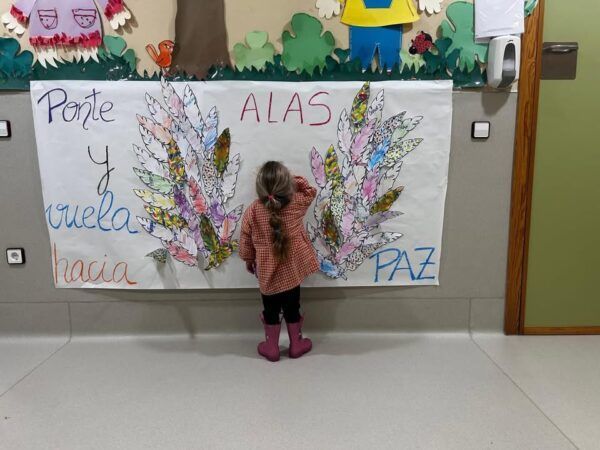 Niña interactuando con un mural sobre la paz en un evento escolar