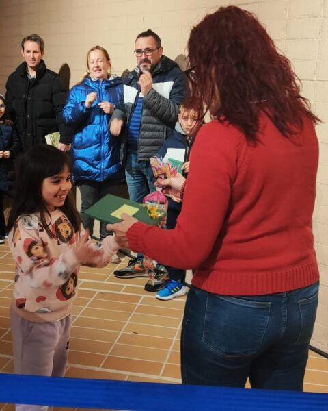 Niña recibiendo un premio en un certamen literario navideño
