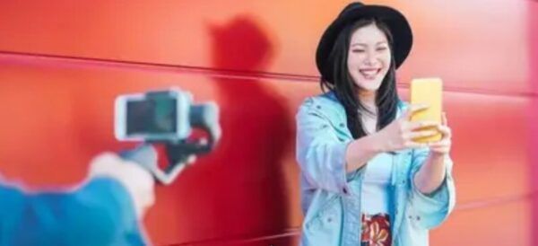 Mujer sonriendo mientras graba un video con un teléfono en China.