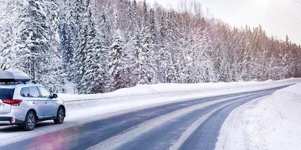 Vehículo en una carretera nevada rodeada de árboles cubiertos de nieve