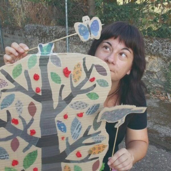 Mujer sosteniendo un árbol de cartón con mariposa en cuentacuentos infantil