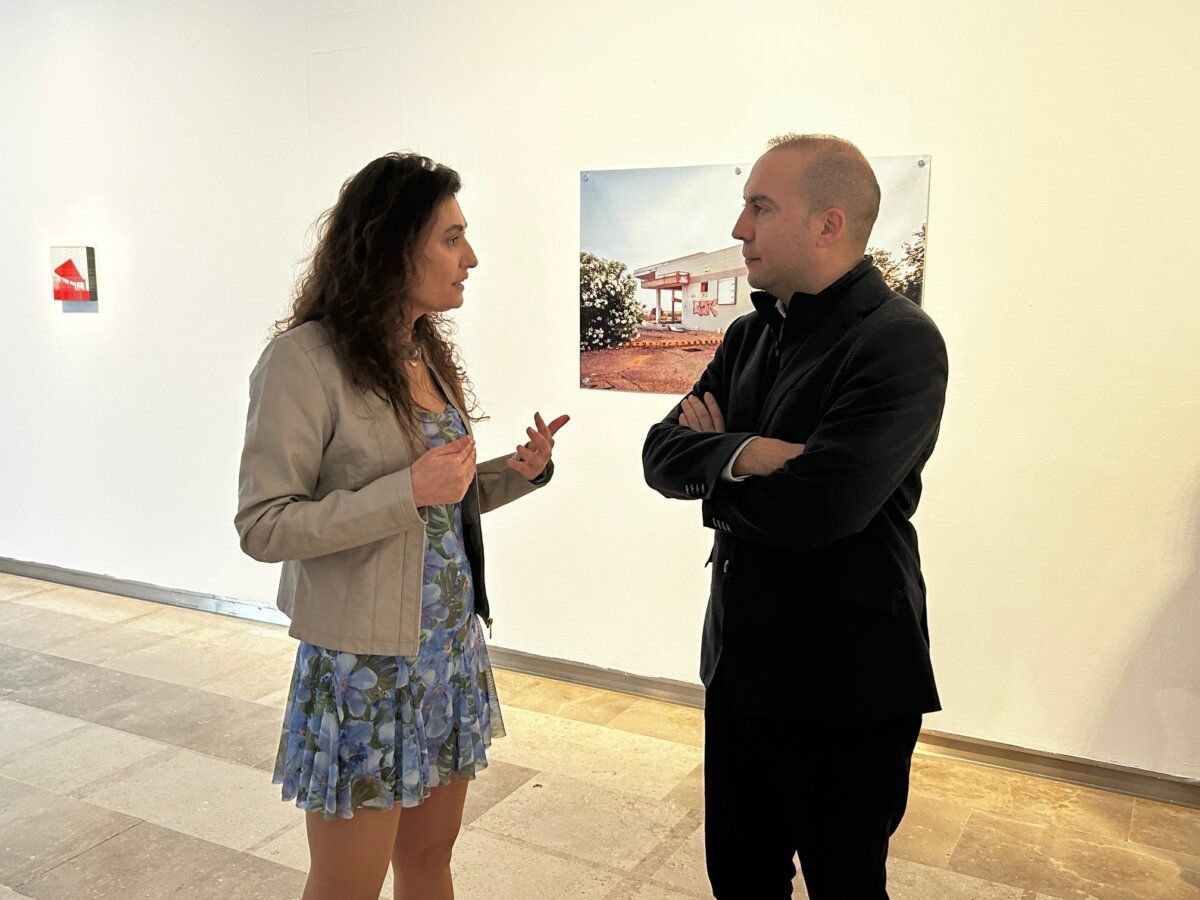 Dos personas conversando en la exposición Más octanos en el DA2