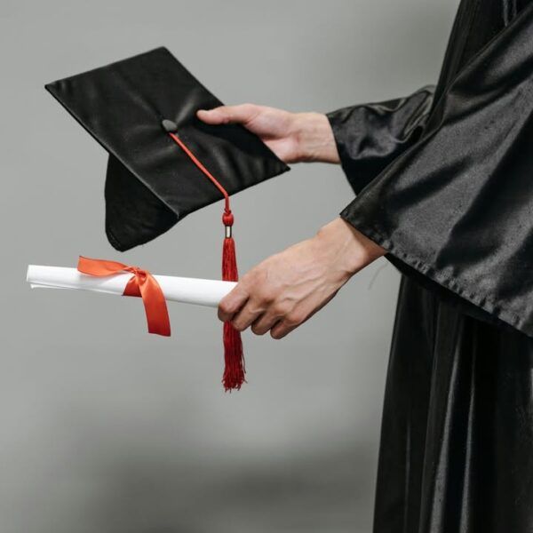 Graduado sosteniendo un diploma y un birrete en ceremonia de graduación