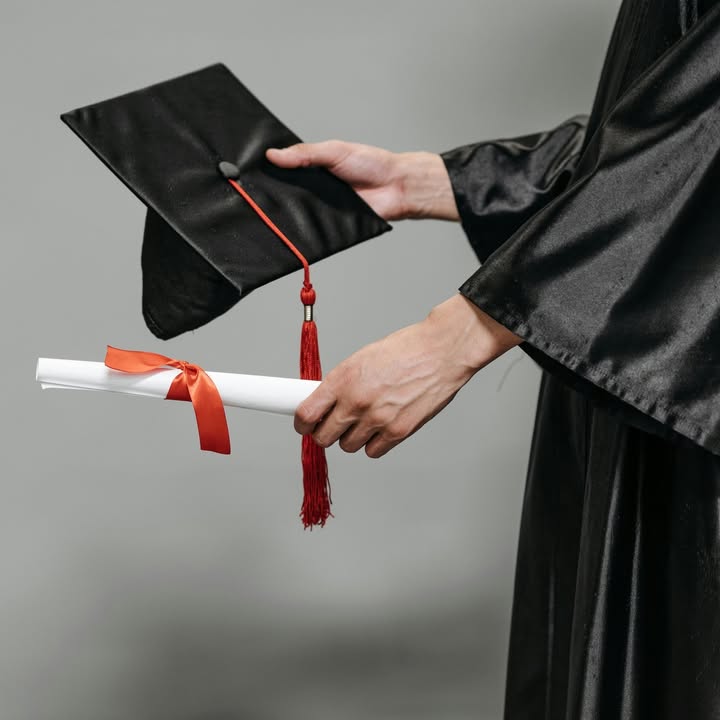 Graduado sosteniendo un diploma y un birrete en ceremonia de graduación