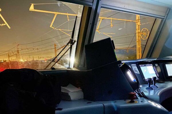 Interior de cabina de tren con vista a las vías y señales eléctricas