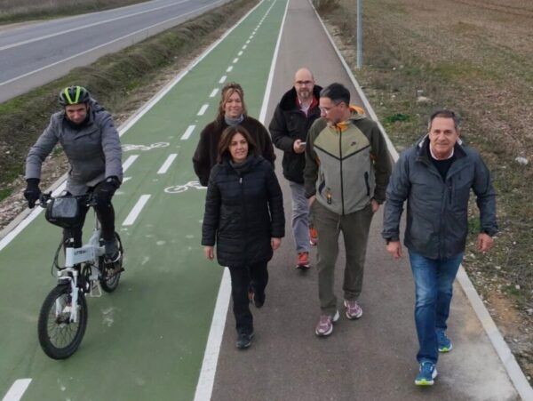 Grupo de personas caminando junto a un ciclista en un carril bici en Villamayor
