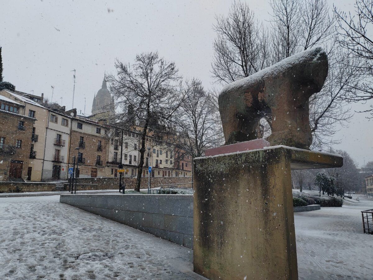 Vista de Salamanca cubierta de nieve con una escultura en primer plano