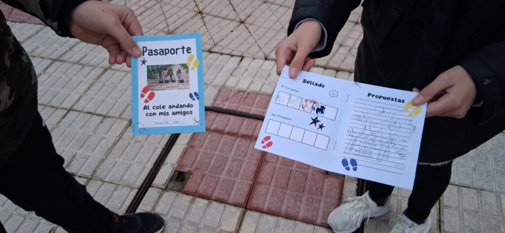 Dos escolares sosteniendo un pasaporte del programa Al cole vamos andando