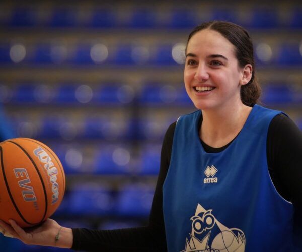 Jugadora de baloncesto sonriente sosteniendo un balón en la cancha