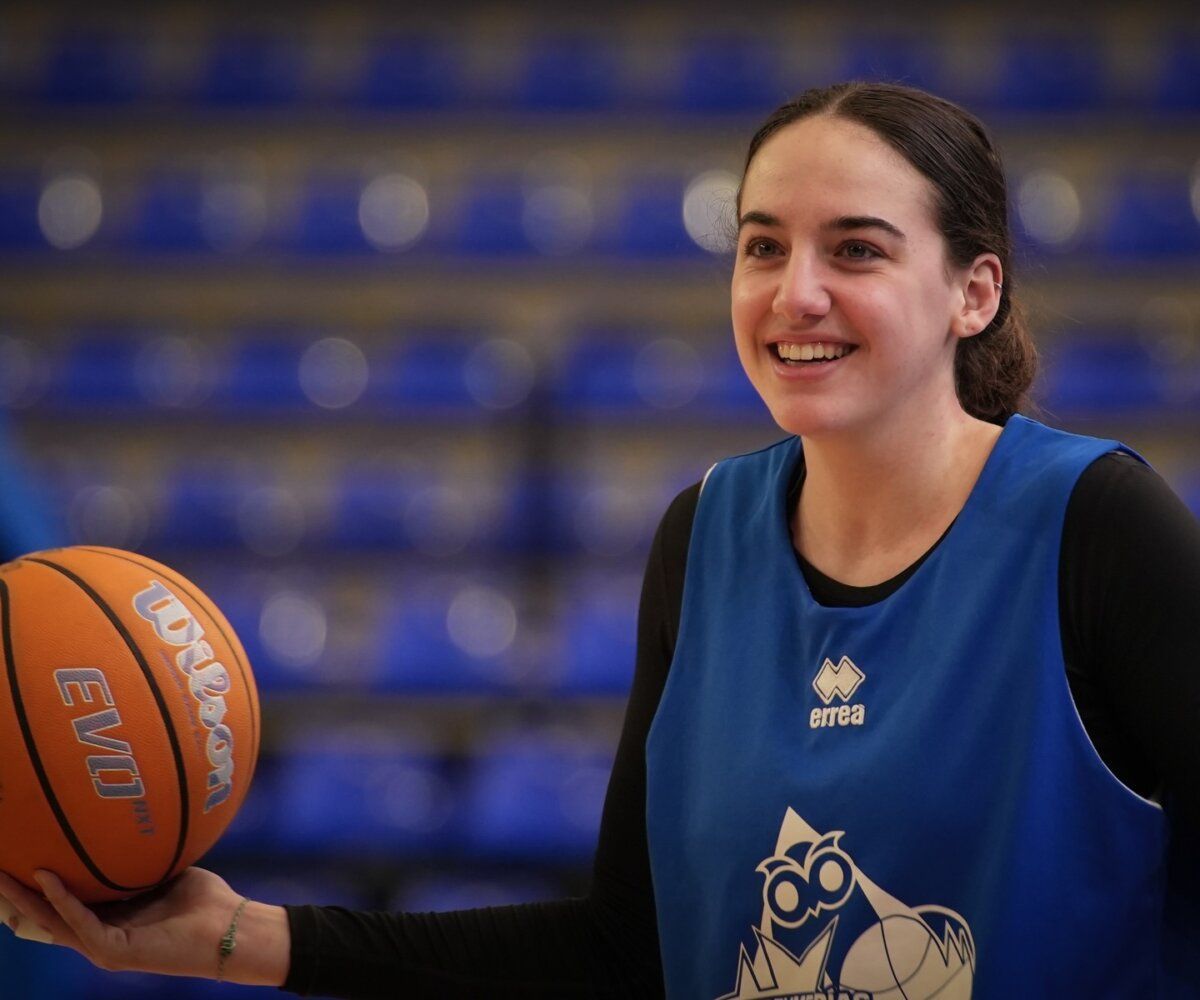 Jugadora de baloncesto sonriente sosteniendo un balón en la cancha