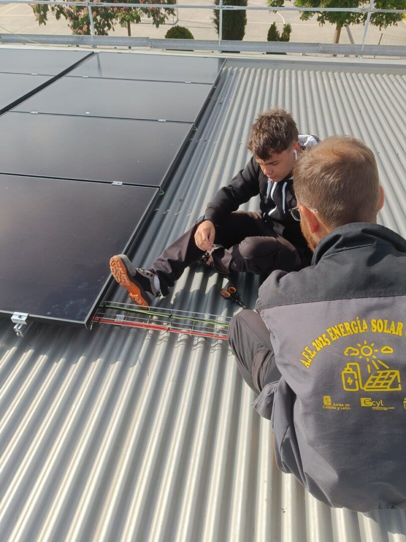 Dos jóvenes trabajando en la instalación de paneles solares en un techo.