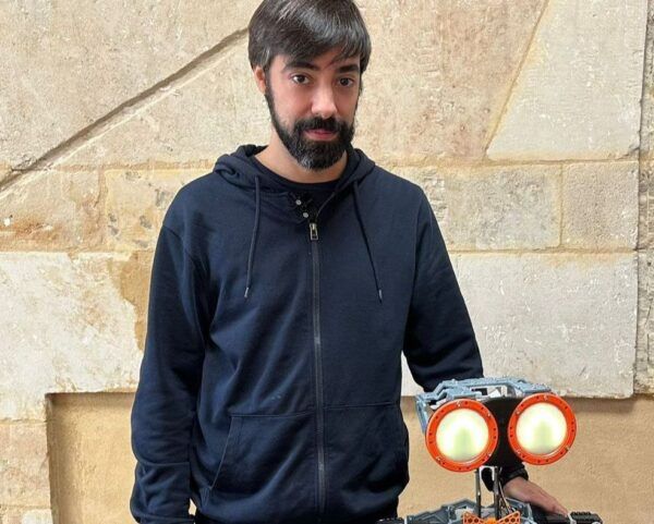 Rubén Martín junto al robot Cocobot en un entorno académico.