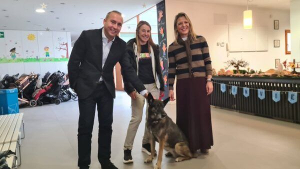 Tres personas en un taller escolar sobre cuidado de mascotas con un perro