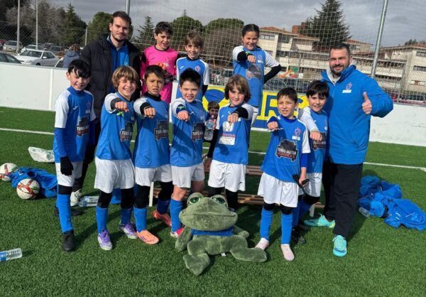 Grupo de niños en un campo de fútbol con brazaletes de la AECC