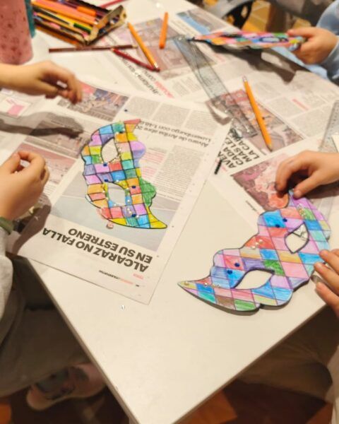Niños creando máscaras de carnaval con colores en una mesa