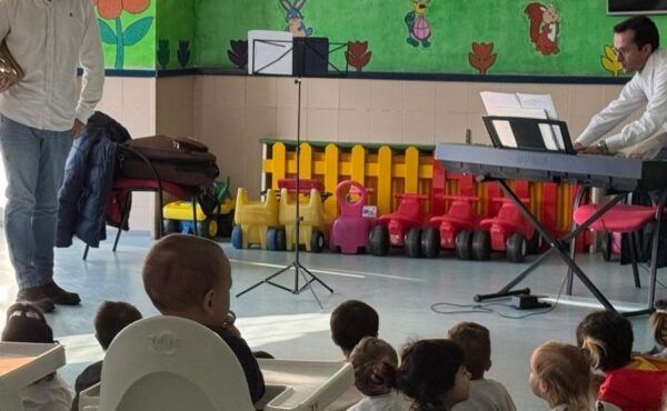 Niños sentados escuchando música en una escuela infantil