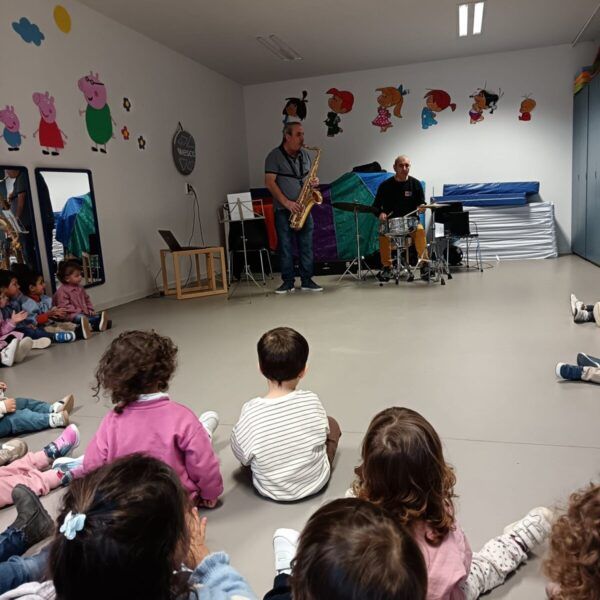 Niños sentados escuchando música en una escuela infantil