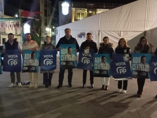 Miembros del PP de Salamanca sosteniendo carteles de campaña en la noche.