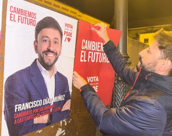 Persona colocando un cartel de campaña del PSOE en Salamanca