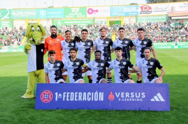 Jugadores de Unionistas CF posando en el campo con un personaje disfrazado