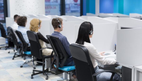 Empleados en un call center usando auriculares en sus estaciones de trabajo