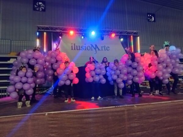 Grupo de personas disfrazadas con globos en un escenario de carnaval.