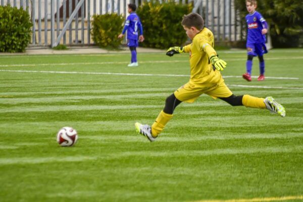 Niño portero del CD Peñaranda lanzando el balón en un partido de fútbol