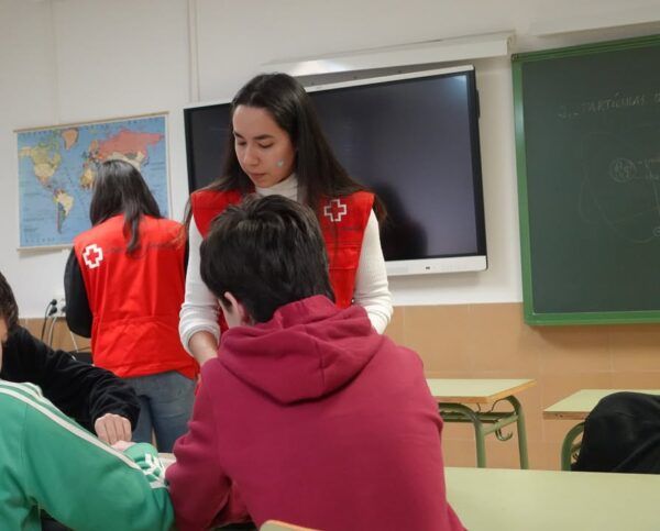 Voluntaria de Cruz Roja interactuando con estudiantes en un aula