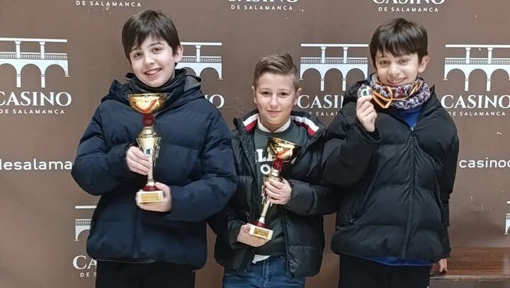 Tres jóvenes ajedrecistas sosteniendo trofeos en el Casino de Salamanca