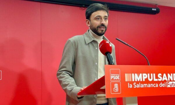 Fran Díaz en una rueda de prensa con micrófono y cartel del PSOE