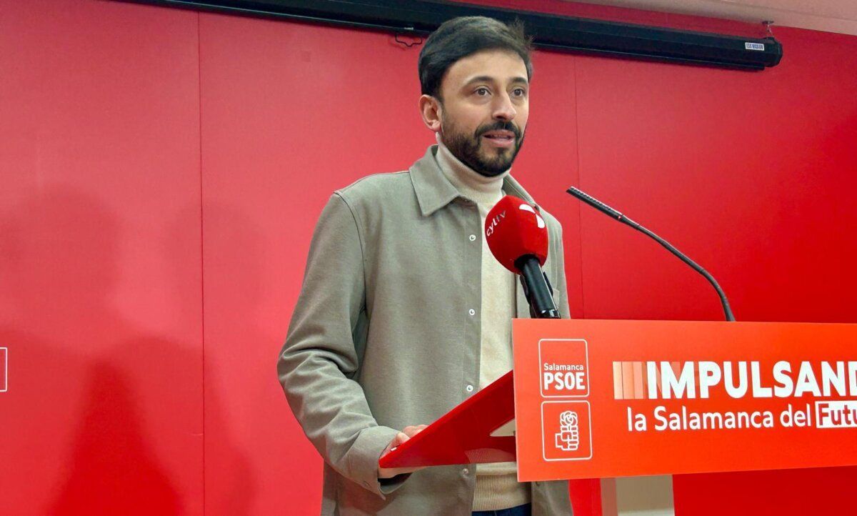 Fran Díaz en una rueda de prensa con micrófono y cartel del PSOE