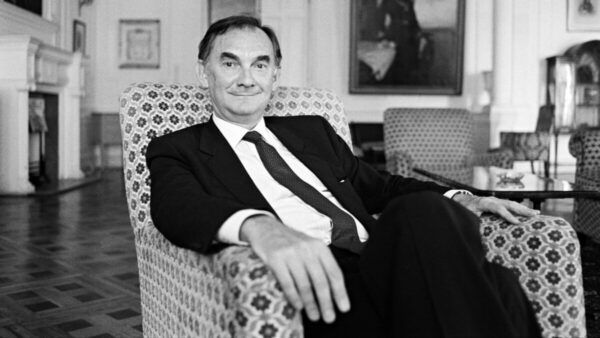 Francisco Tomás y Valiente sentado en un sillón, sonriendo.
