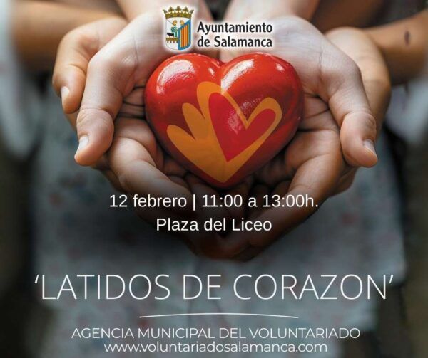 Manos sosteniendo un corazón rojo con un diseño colorido en un evento de voluntariado.