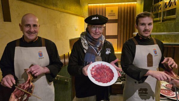 Tres hombres sosteniendo platos con jamón ibérico en Guijuelo