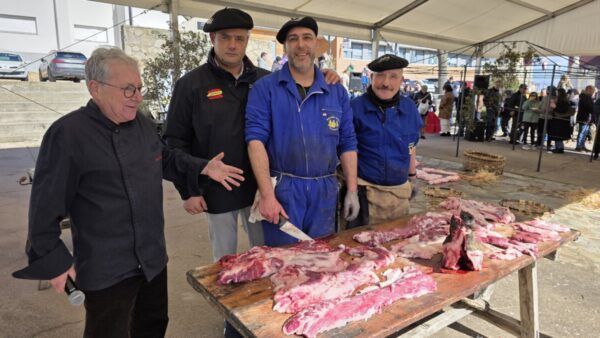 Participantes en la Matanza de Carnaval en Guijuelo, con cerdo ibérico en mesa.