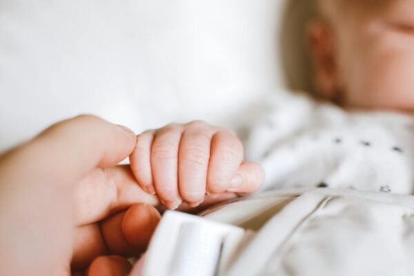 Mano de un adulto sosteniendo la mano de un bebé recién nacido