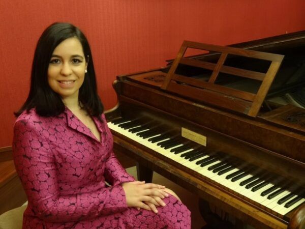 Virginia Sánchez Rodríguez posando junto a un piano en un ambiente acogedor