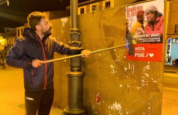 Persona colocando un cartel de campaña del PSOE en Salamanca
