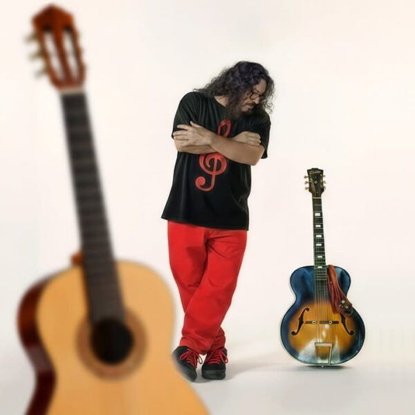 Raimundo Amador posando junto a su guitarra en un fondo claro