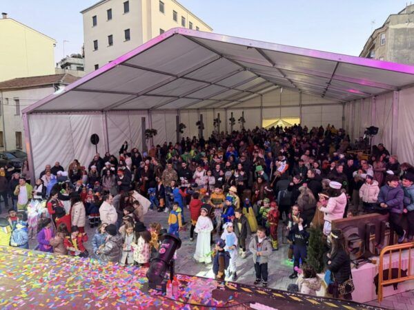 Multitud de personas celebrando en un evento de carnaval bajo una carpa.