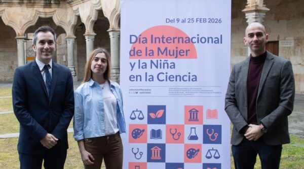 Tres personas posando junto a un cartel del Día Internacional de la Mujer y la Niña en la Ciencia