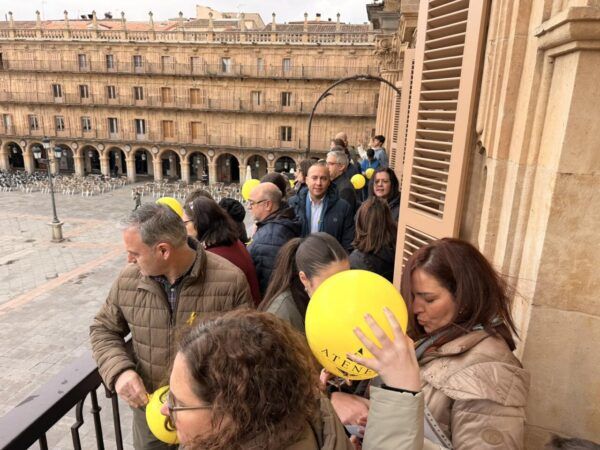Personas en el balcón del Ayuntamiento de Salamanca con globos amarillos