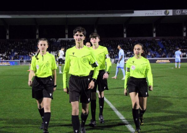 Grupo de árbitros jóvenes caminando en un campo de fútbol