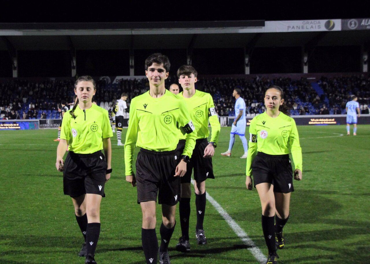 Grupo de árbitros jóvenes caminando en un campo de fútbol