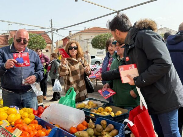 Miembros del PSOE interactuando con vecinos en un mercadillo