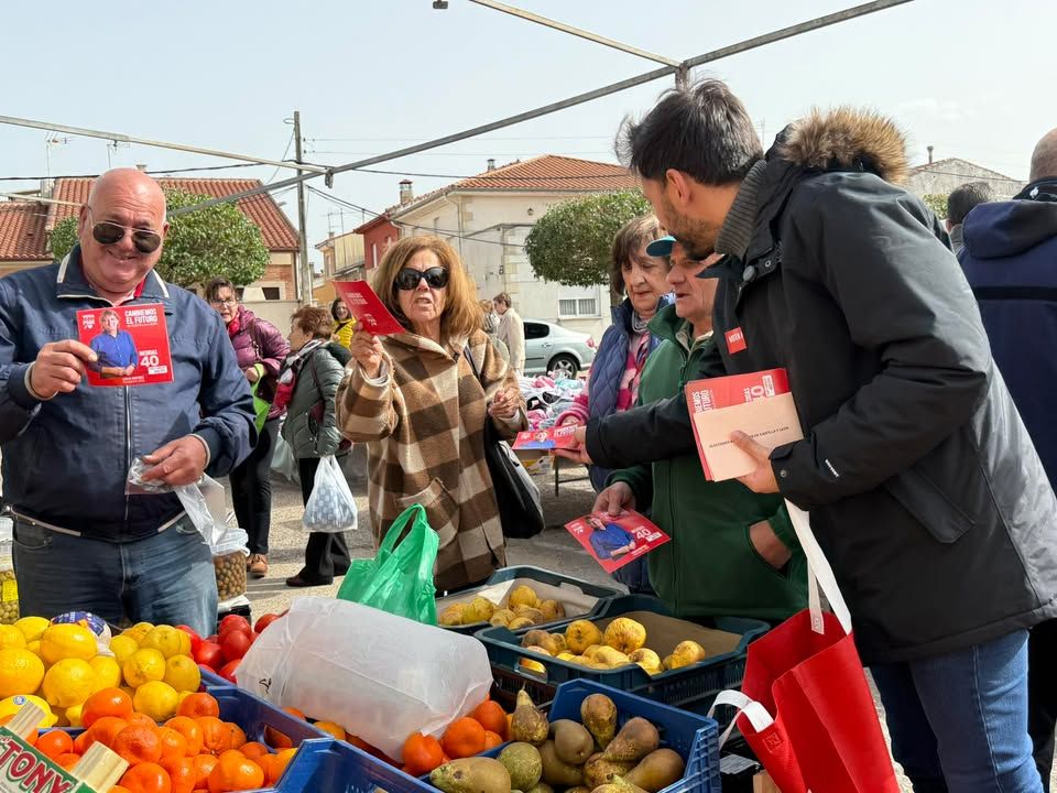 Miembros del PSOE interactuando con vecinos en un mercadillo
